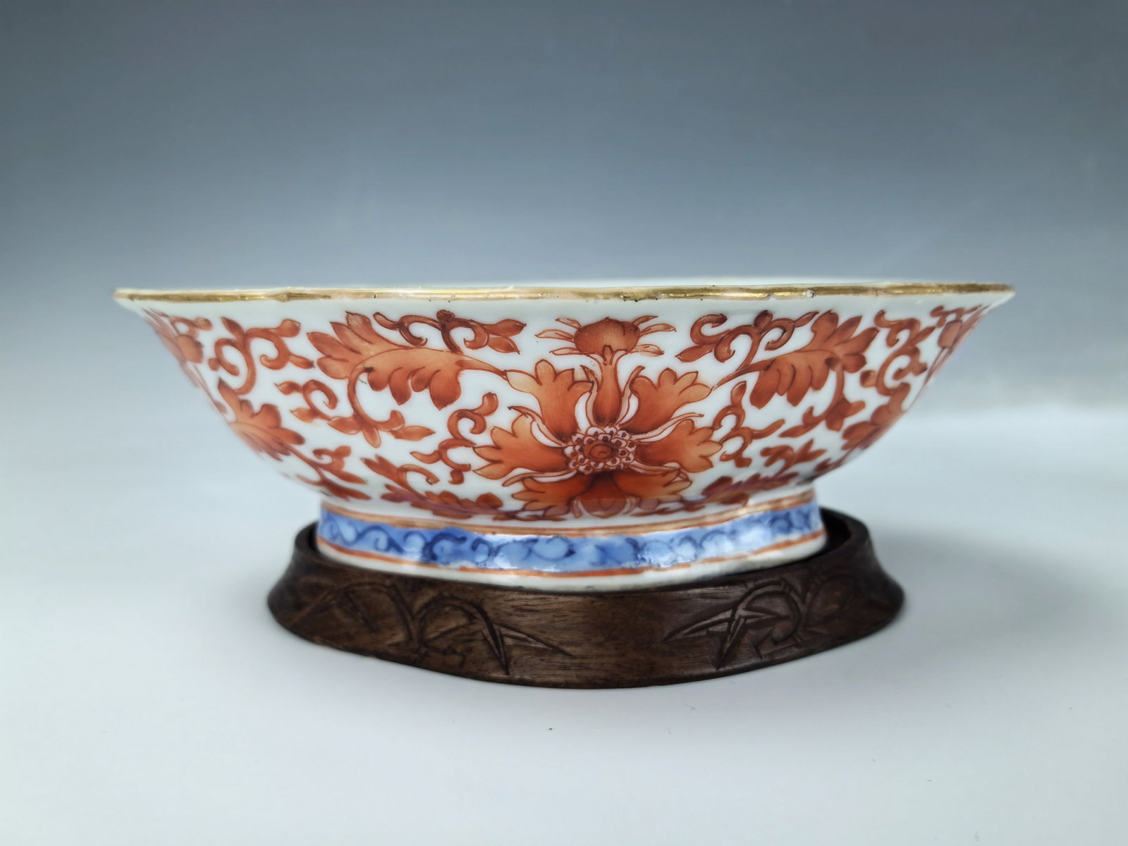 A Chinese Iron Red Porcelain Bowl with Wood Stand: Porcelain Narcissus Bowl with Iron Red painting of Scrolling lotus with Wood Stand,W 19 cm (7.6 in.) x D 14.3 cm(5.6 in.)x H 5.8 cm(2.3 in.), Preview from Apr. 22nd to 26th from 1:00 PM TO 5:00 PM Eas