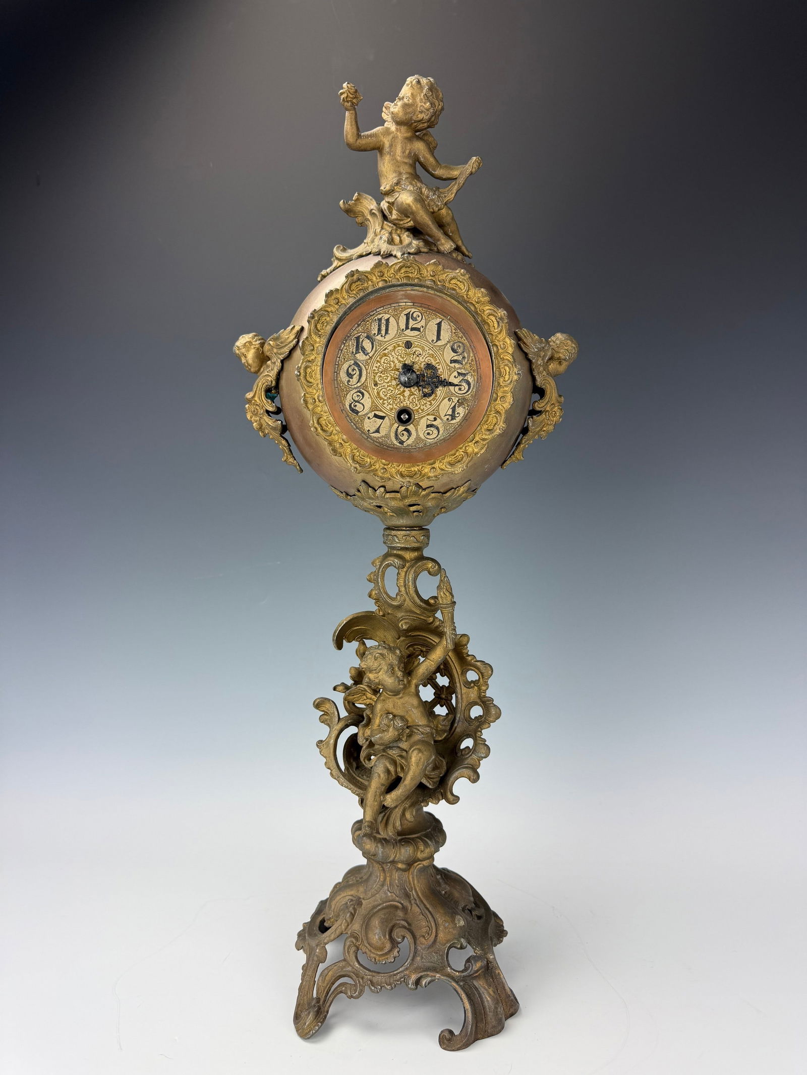 Antique Bronze Cherub Standing Clock: Antique Bronze Cherub Standing Clock,H 60 cm(23 in.).Preview from Feb 23rd to 27th from 1:00 PM TO 5:00 PM Eastern Time, Location: 15229 Display Court, Rockville, MD 20850.