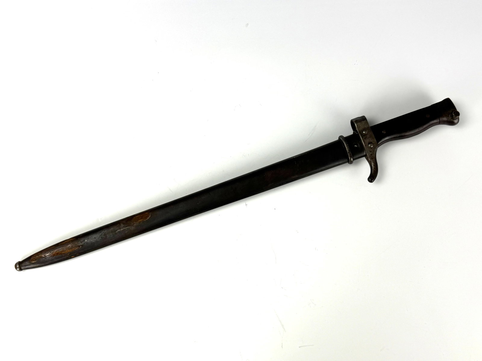 A WWII military bayonet with a grooved blade and a worn metal sheath (1 of 4)