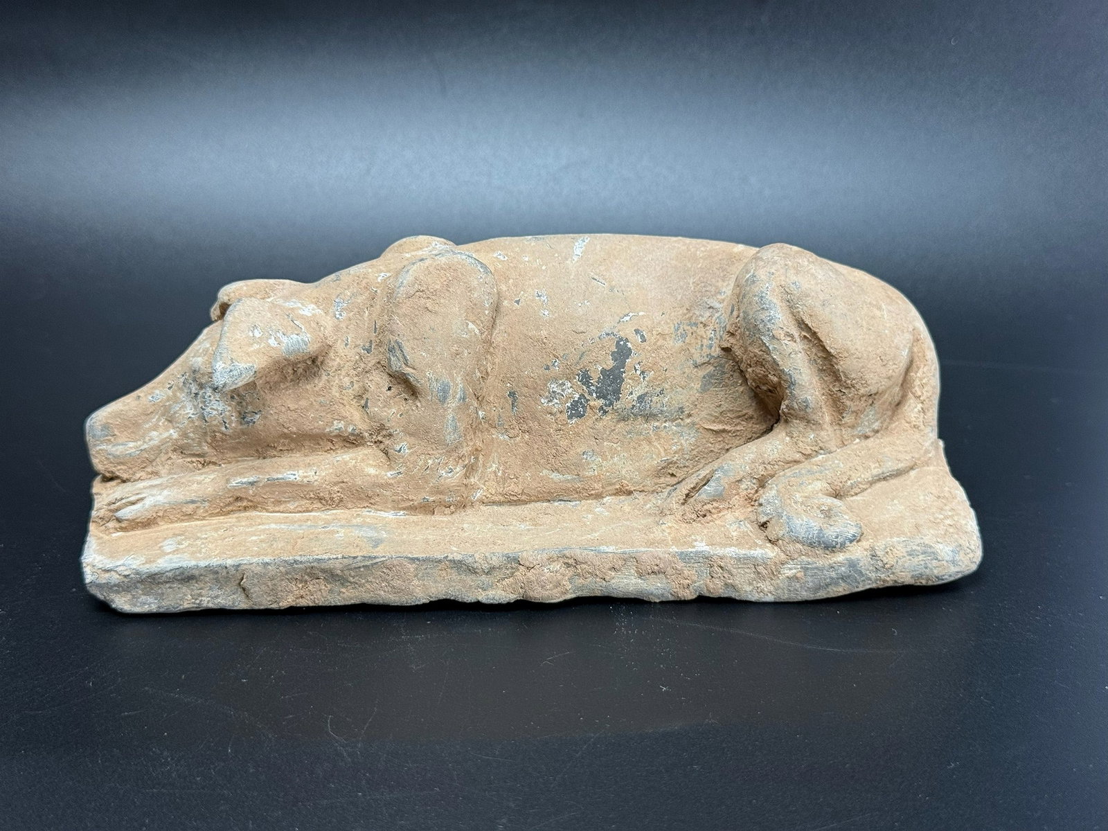 A Chinese Six Dynasty Grey Pottery Figure of a Crouching Dog: A Chinese Six Dynasty Grey Pottery Figure of a Crouching Dog. L 16cm(6.3in.) x W 8cm(3.1in.) x H 6cm(2.4in.). Provenance from Dr. Constantine collection, Acquired from Kitty Higgins.Preview from June 