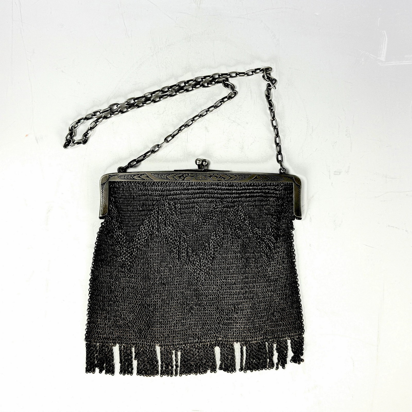A Vintage European Silver Mesh Purse: Metallic Mesh Flapper Bag. Bag: W 19cm(7.5in.) x H 19cm(7.5in.). Belt : 70cm(27.6in.). Preview from June 22nd to 26th from 1:00 PM TO 5:00 PM Eastern Time, Location: 15229 Display Court, Rockville, MD