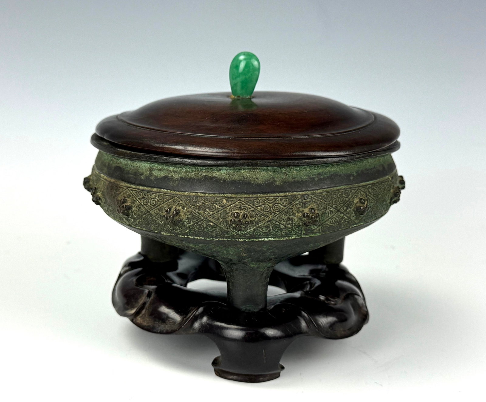 Antique Chinese Bronze Tripod Censer Wooden Lid and Stand: Antique Chinese Bronze Censer with Wooden Lid and Jade Finial, on Carved Wooden Stand. D 13.5 cm(5.3 in.) x H 12.7 cm(5 in.). Preview from Aug 24th to 28th from 1:00 PM TO 5:00 PM Eastern Time, Locati