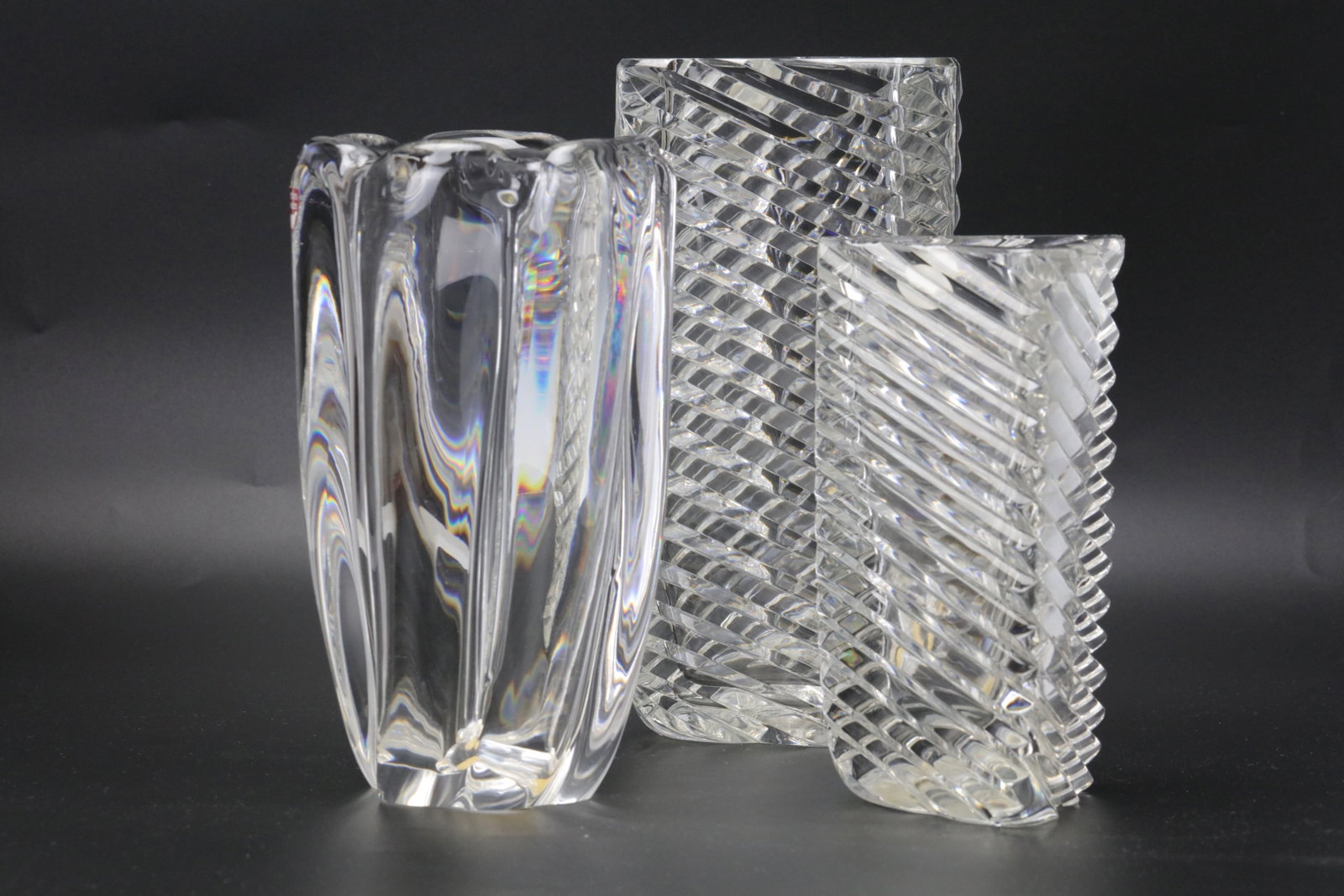 Set of Three Clear Crystal Vases: Set of Three Clear Crystal Vases, One Orrefors Sweden Rounded Ribbed Form and Two Rectangular Cut Pattern Designs. H 15 cm(6 in.) to 20.5 cm(8 in.).?Preview from Aug 24th to 28th from 1:00 PM TO 5:00 