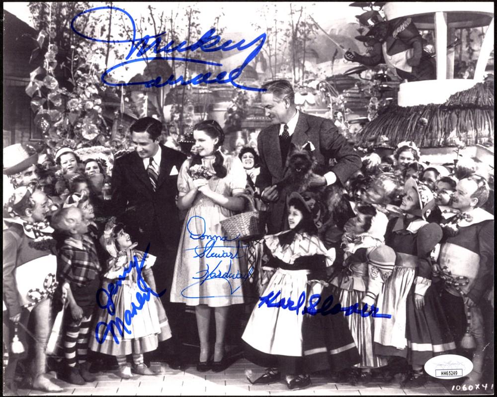 "Wizard Of Oz" 8x10 Photo Cast-Signed by (4) with: Photo measures 8" x 10" in size and has been hand-signed by Mickey Carroll (D. 2009), Jerry Maren (D. 2018), Donna Stewart Hardway (D. 2008), And Karl Slover (D. 2011). The lot / autograph(s) includes