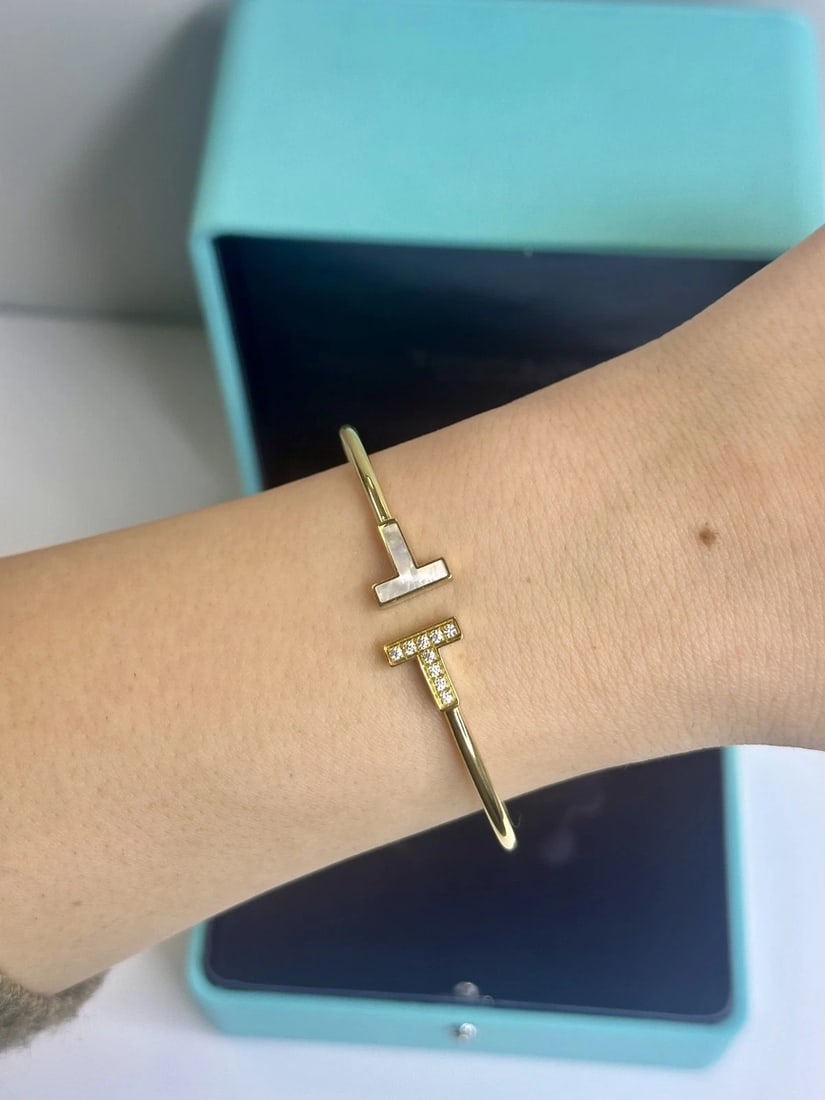 Tiffany&Co. T Wire Diamond 0.11ct Bangle Bracelet In 18K Yellow Gold: This bracelet features 9 round-cut diamonds totaling 0.11ct, set in 18K yellow gold with a bangle style design.. Comes With Original Box. Condition: Pre-owned - Good,Brand: Tiffany & Co,Number of Diam