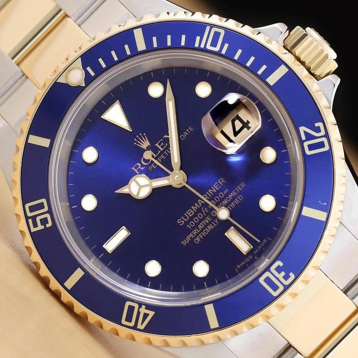 2007 PAPER ROLEX SUBMARINER 16613LB NO HOLES 18K GOLD 40MM STEEL WATCH: This is an authentic Rolex Submariner Date 16613LB no holes 40mm blue dial watch with 18K yellow gold and stainless steel oyster bracelet, blue rotatable 18K yellow gold bezel, and original Rolex