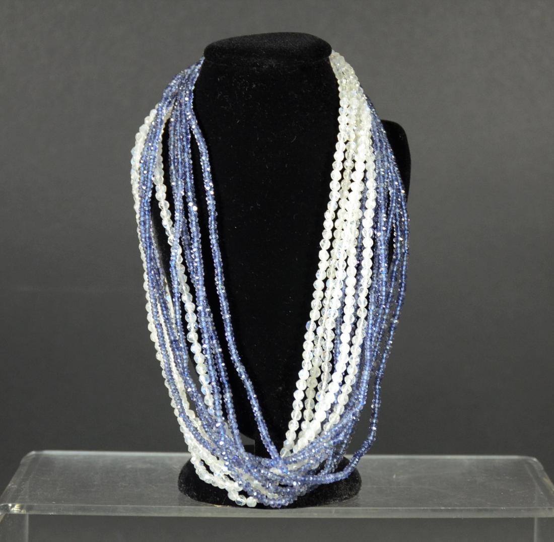 Twelve Strand Iolite & Moonstone: Torsade Necklace, having faceted beads, 14K white gold clasp. 16"l. From Claus Vollrath Inc., Mt Kisco, New York.