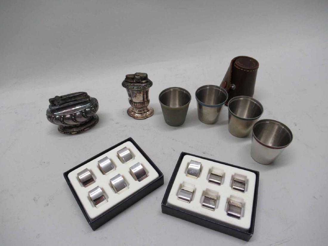 FOUR GERMAN WHITE METAL AND ENAMEL SHOT GLASSES: Together with twelve German metal place card holders and two silver plate lighters.