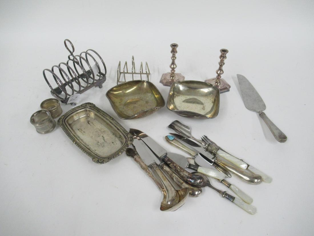 Group of Silver Plate Table Articles: Including two toast racks, one Made in England, two square dishes, pair of candlesticks,four pistol handled knives and a butter dish lid. Together with a sterling silver handled cake server and cheese
