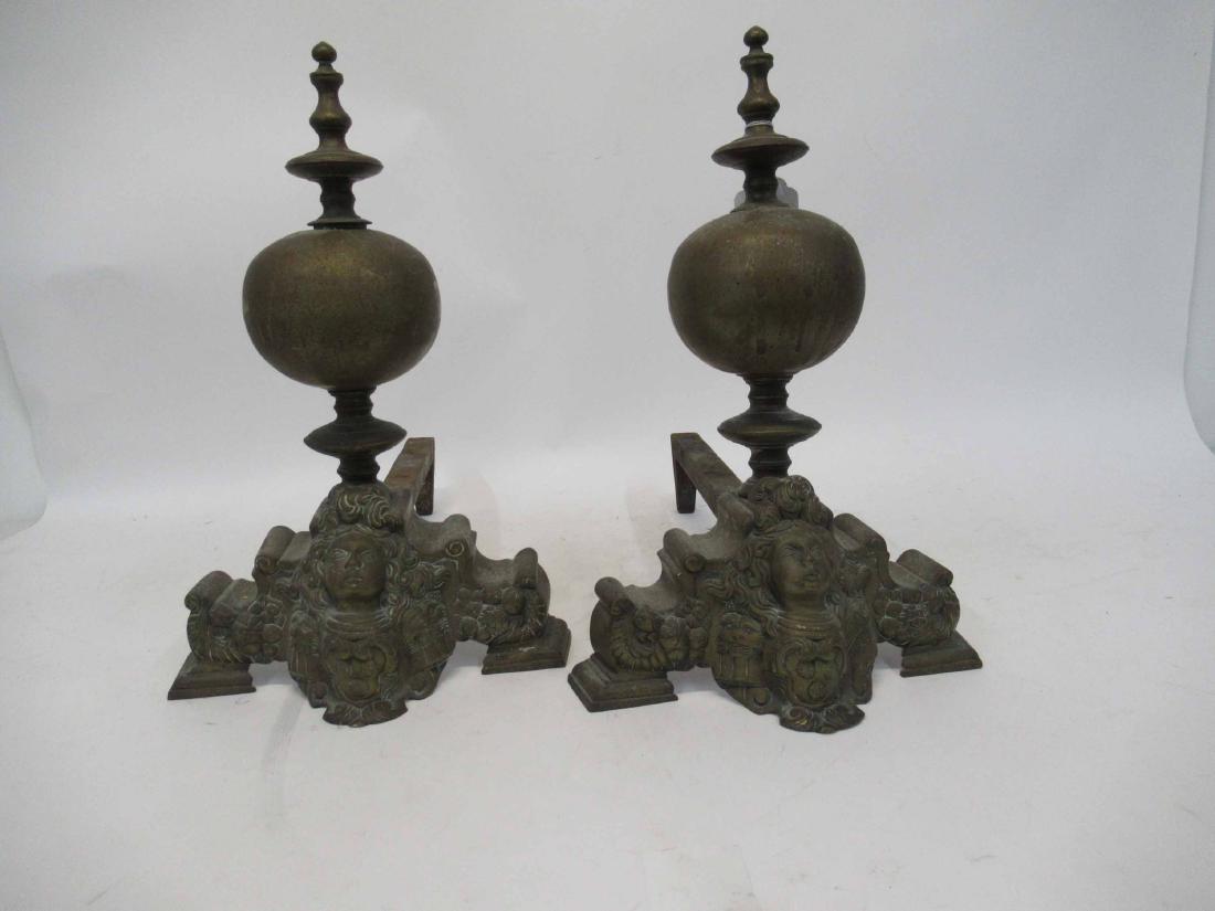 Pair of Brass and Iron Andirons: Depicting figural face with flanked by fu dogs. 16" tall x 18 1/2" deep x 10" wide