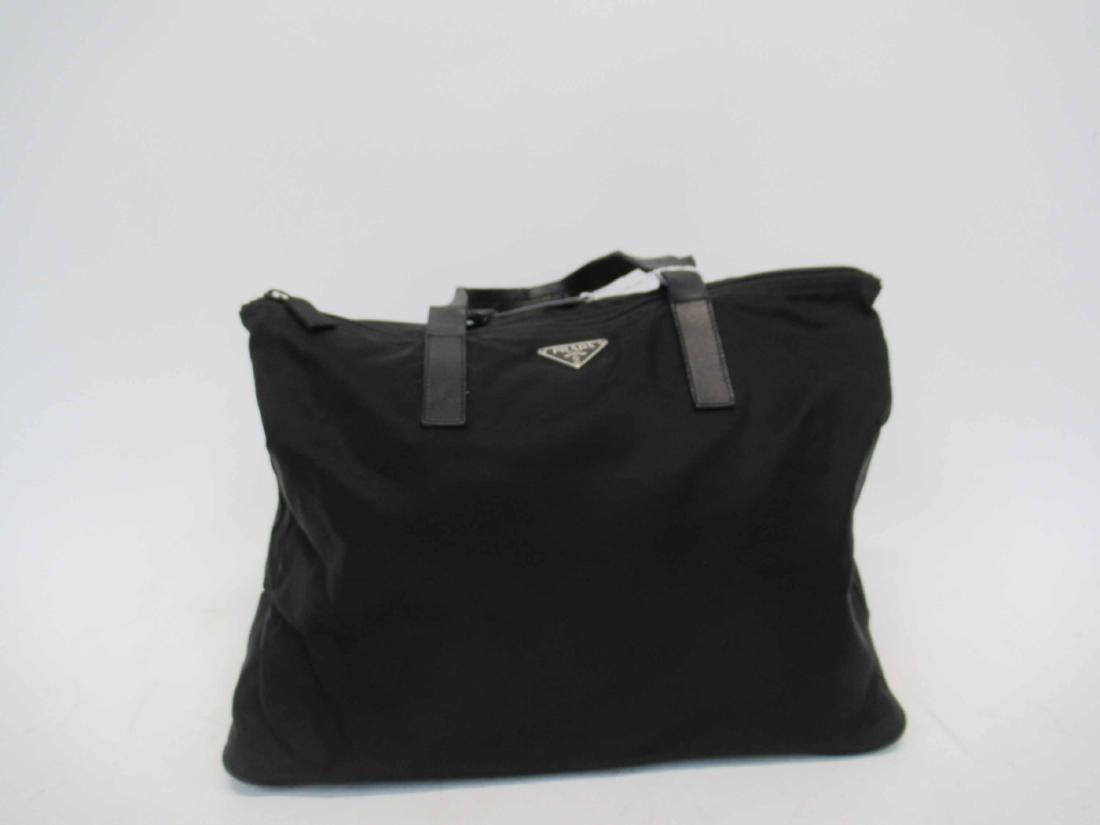 Prada Black Nylon With Leather Tote Bag: With double handles, front with black triangular Prada tag, interior black fabric signature lining, one long zipper pocket, metal tag Prada Made in Italy. 10"h x 15"w x 8"d, straps, 5-1/2"drop. Prada,