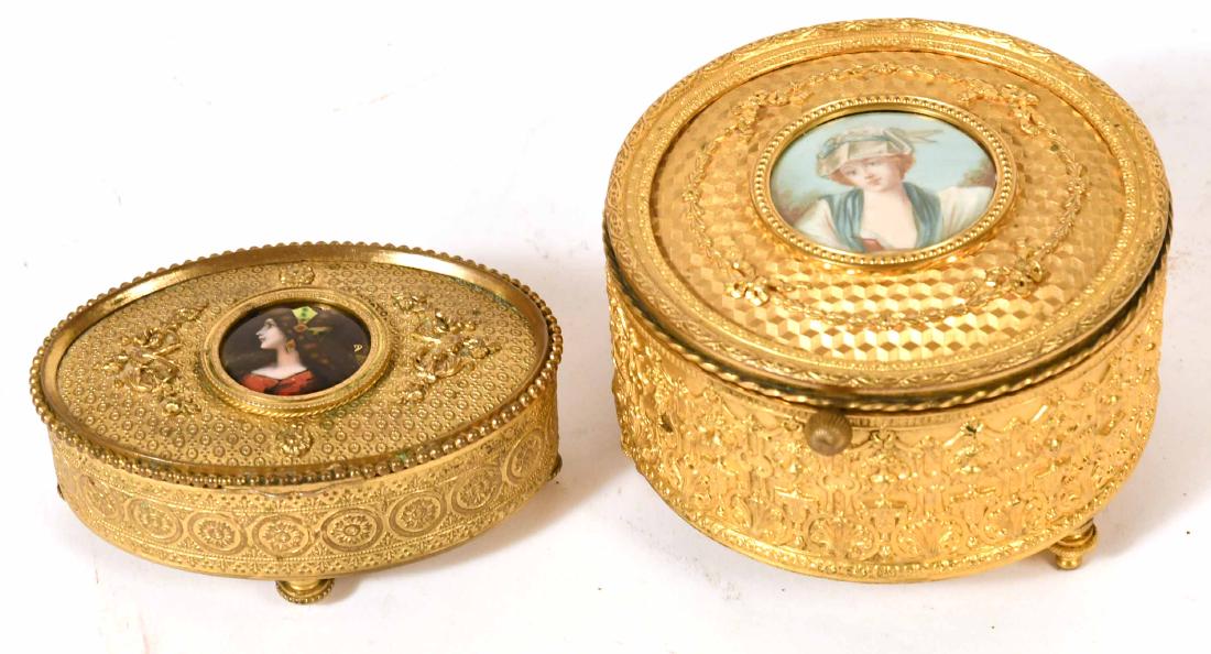 Two French Git Metal Jewelry Boxes: Both with center medallion portraits of girls, one fitted as a music box and lid opening to a clock. 3 x 4 3/4"d and 1 1/2"h x 4 1/2"l x 3"w