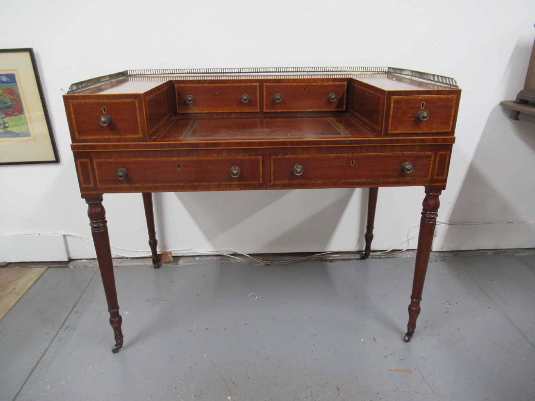 Edwardian Mahogany Writing Desk: Brass gallery top with banded inlay throughout and leather writing surface. Bent gallery, some surface distress. 35" tall x 42" x 24 1/2"