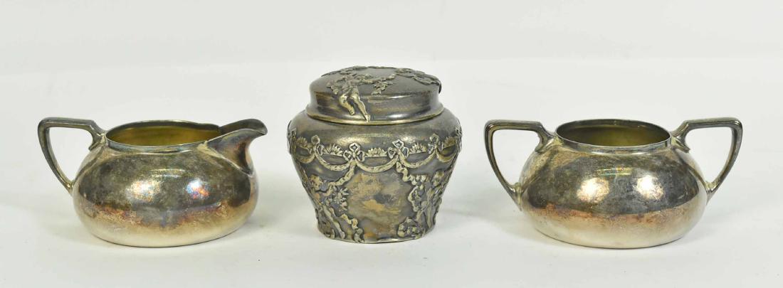 George Shiebler & Co Sterling Silver Dresser Jar: Stamped underside Sterling 4530, repousse putti and swag decoration, weight approx. 5 T.O., 3-1/4"h. Together with a Rogers silver plated open sugar bowl and cream jug set.