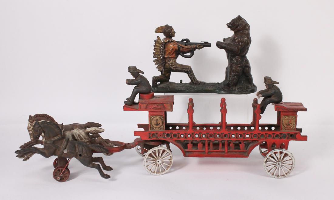 Two Painted Cast-Iron Toys: Comprising, a horse and carriage, with two riders and three horses, and an Indian and bear piggy bank. 9-1/2"h x 25"w x 5-1/2"d 7-1/2"h x 10-1/4"w x 3-1/4"d