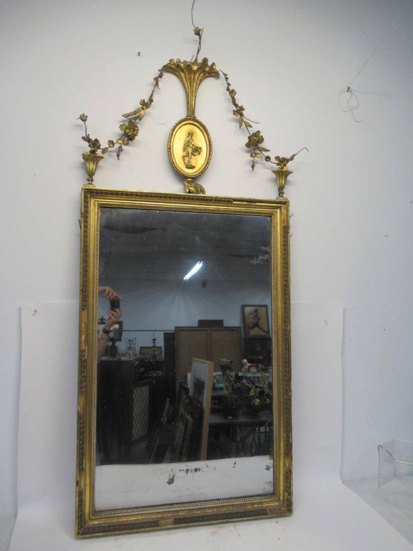 Antique Giltwood Hanging Wall Mirror: Antique Giltwood Hanging Wall Mirror having oval crest depicting maiden with basket. Used condition, wear, worn, repairs, missing pieces or parts. 64 1/2" tall x 26 1/2" x 2" thick.
