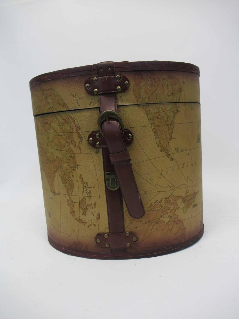 Map Decorated Hat Box: Map Decorated Hat Box. Hat box with map of the world decoration and red leather straps. Used Condition, wear, worn, surface distress. 14" tall x 14 3/4" x 11 1/2"