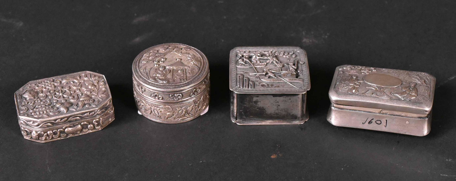 Four Chinese Export Silver Small Boxes: Including one hinged lidded snuff box, lid with figures withing landscape and oval vacant cartouche, square box with river scene, circular box, with figure, pagoda and clouds, fourth rectangular with 