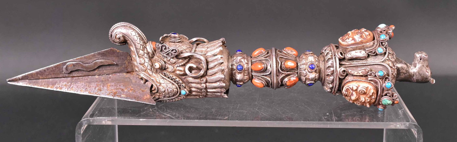Tibetan Buddhist Three Headed Ritual Dagger: Horse head top, silvered metal bezel set with turquoise, coral and lapis lazuli stones, three sided triangular stake/blade,, 10-1/4"l. Provenance: Property from the Collection of Myrna and Bernard Pos