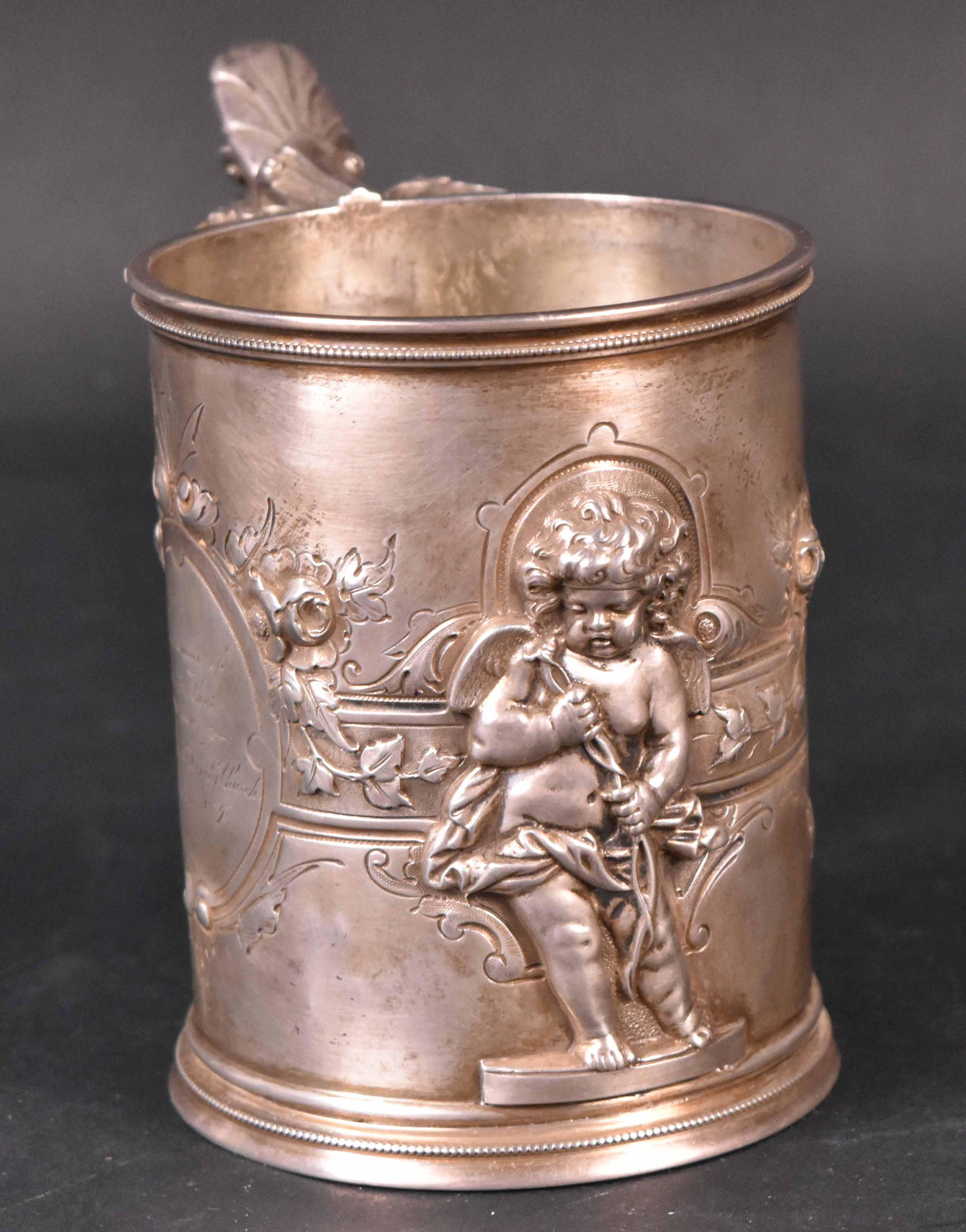 Wood & Hughes American Silver Presentation Cann: Makers Mark W & H, Wood & Hughes, New York circa 1865, heavily embossed Putti, strapwork decoration, each side cartouche with engraved inscription, "Frederick Fitzgerald Easter 1867" "In Memory of His