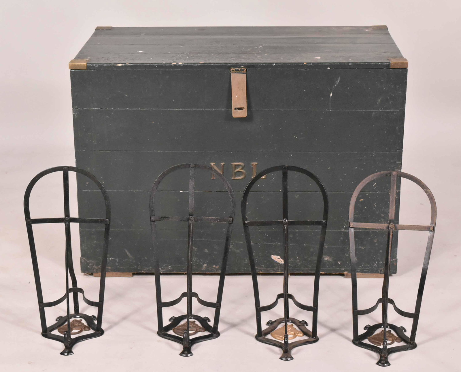 The Natica Blair Lorillard Tack Trunk: 20th C., green-painted and cedar-lined. Together with four metal wall mounted saddle racks, stamped Made in England. 5 pieces Saddle Racks: 11"h x 21"w x 10-1/2"d. Trunk: 30-1/2"h x 43-1/2"w x 24"d Pr