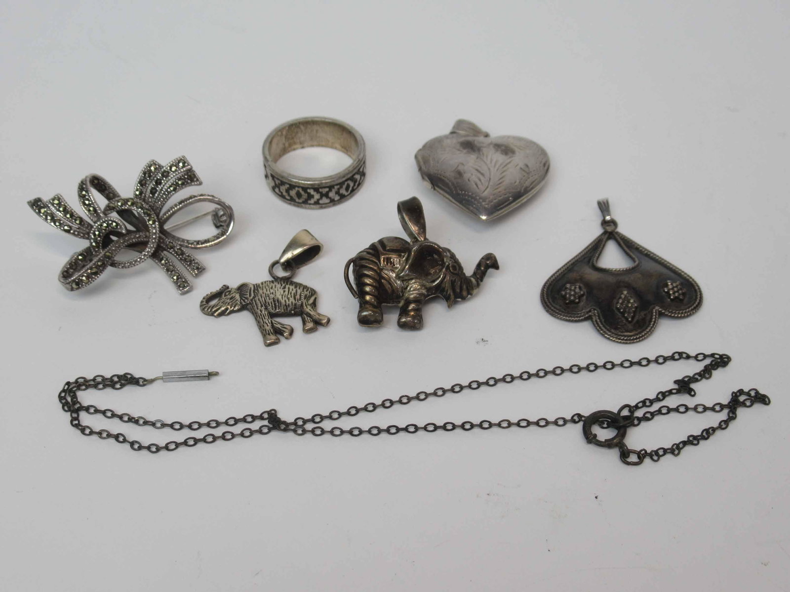 Group of Silvered Jewelry: Including a marcasite bow pin, ethnic band ring, stamped,two elephant pendants, one stamped 925, heart-form locket, pendant stamped 925.