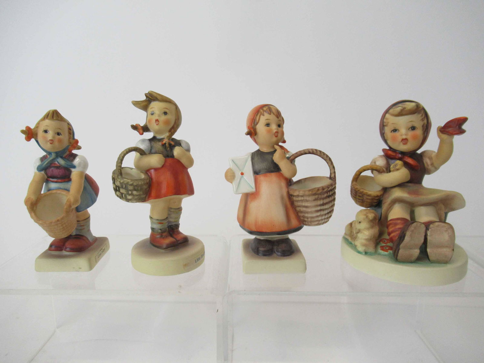 Four M. J. Hummel Goebel Figurines: Four M. J. Hummel Goebel Figurines including Farewell, Little Helper, Little Shopper and Meditation. Used condition, crazing to base on one, chip to hair on little helper, chip to finger of Meditation