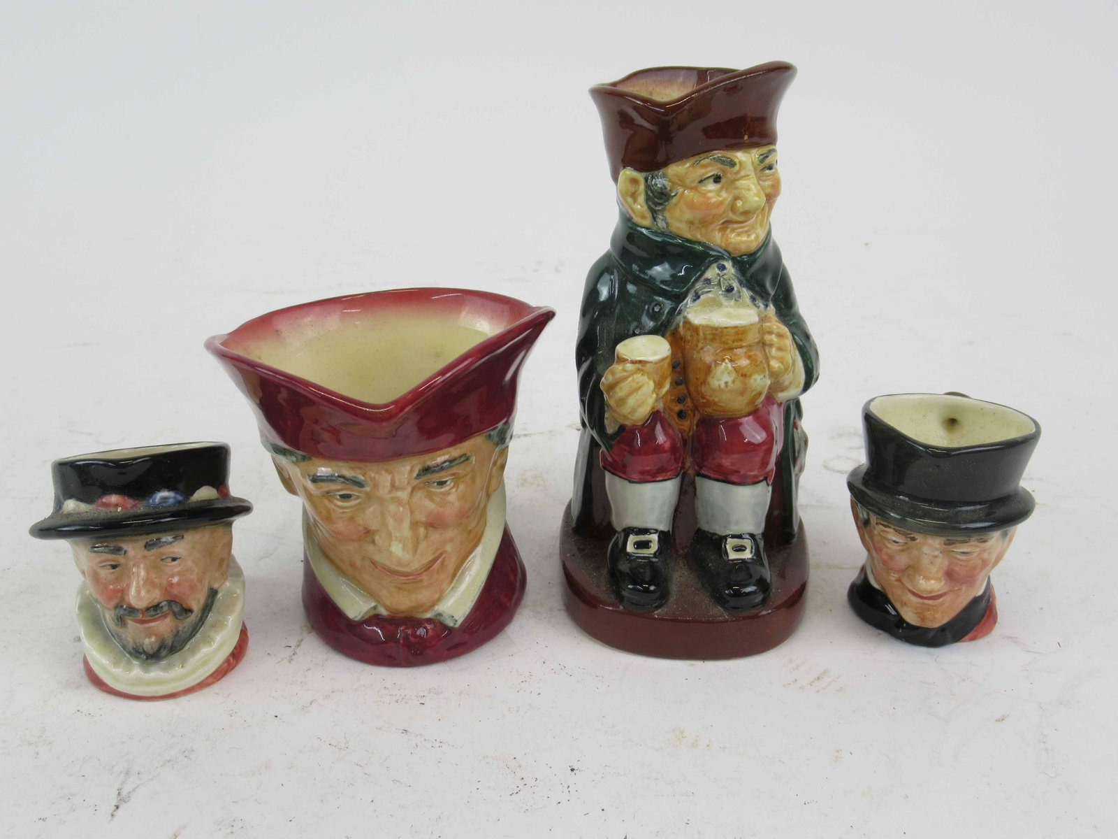 Royal Doulton Toby Mugs: Royal Doulton Toby Mugs. Comprising John Peel, Beefeater and two additional mugs.Used condition, wear, in need of a bath. Largest size 5 1/2" T.