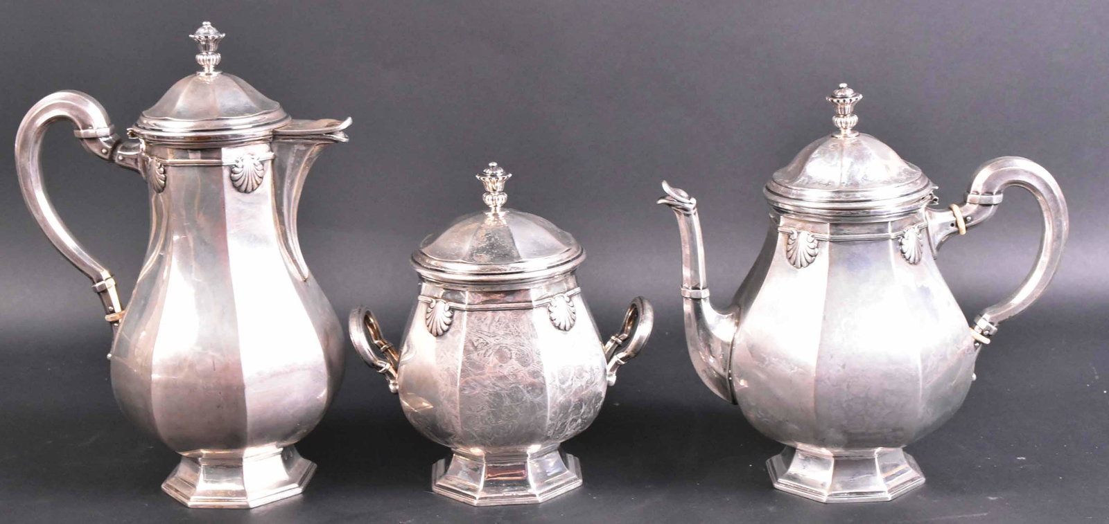 German 800 Silver Three Piece Coffee Set: Comprising: a three piece hexagonal shell decorated coffee pot, teapot, and a covered double handled sugar. Lid to pot is detached. Apx, 74 t.o. and 10"h.