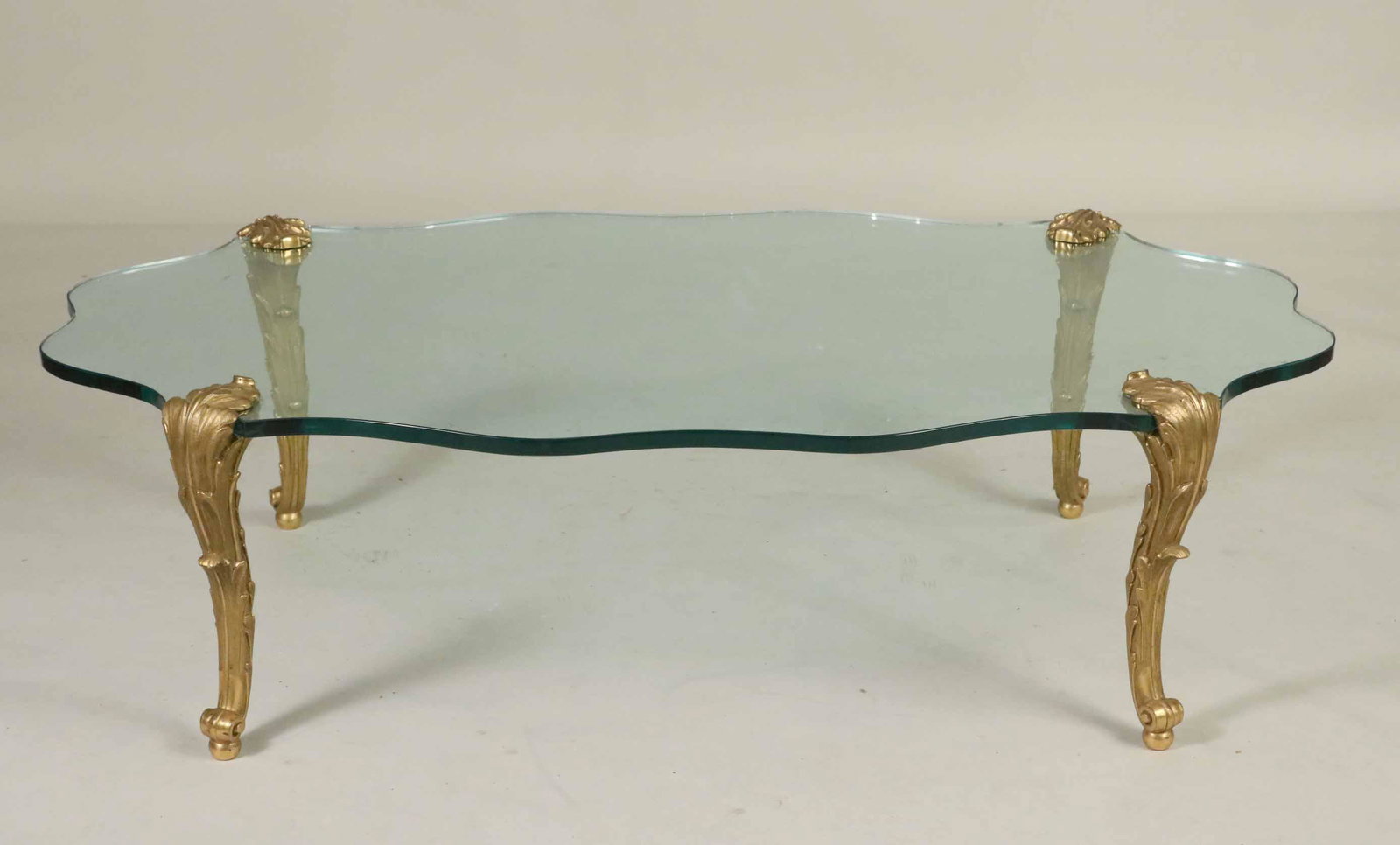P.E. Guerin Gilt-Bronze and Glass Coffee Table: Marked under foot, P.E. Guerin Inc, New York, of shaped oval cartouche form. 16"h x 55-1/2"w x 31"d Provenance: Property from the Collection of Myrna and Bernard Posner.
