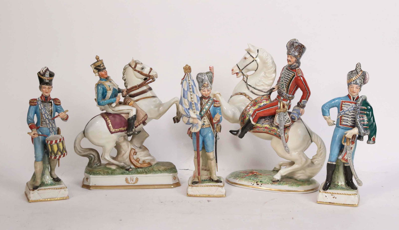 Five Porcelain French Military Figures: Comprising a Capo-di-Monte Husar on horseback, a Royal Crown Derby solider on horseback, and three Capo di Monte figures. Losses to fingers on one. From 9-1/4"h to 11"h
