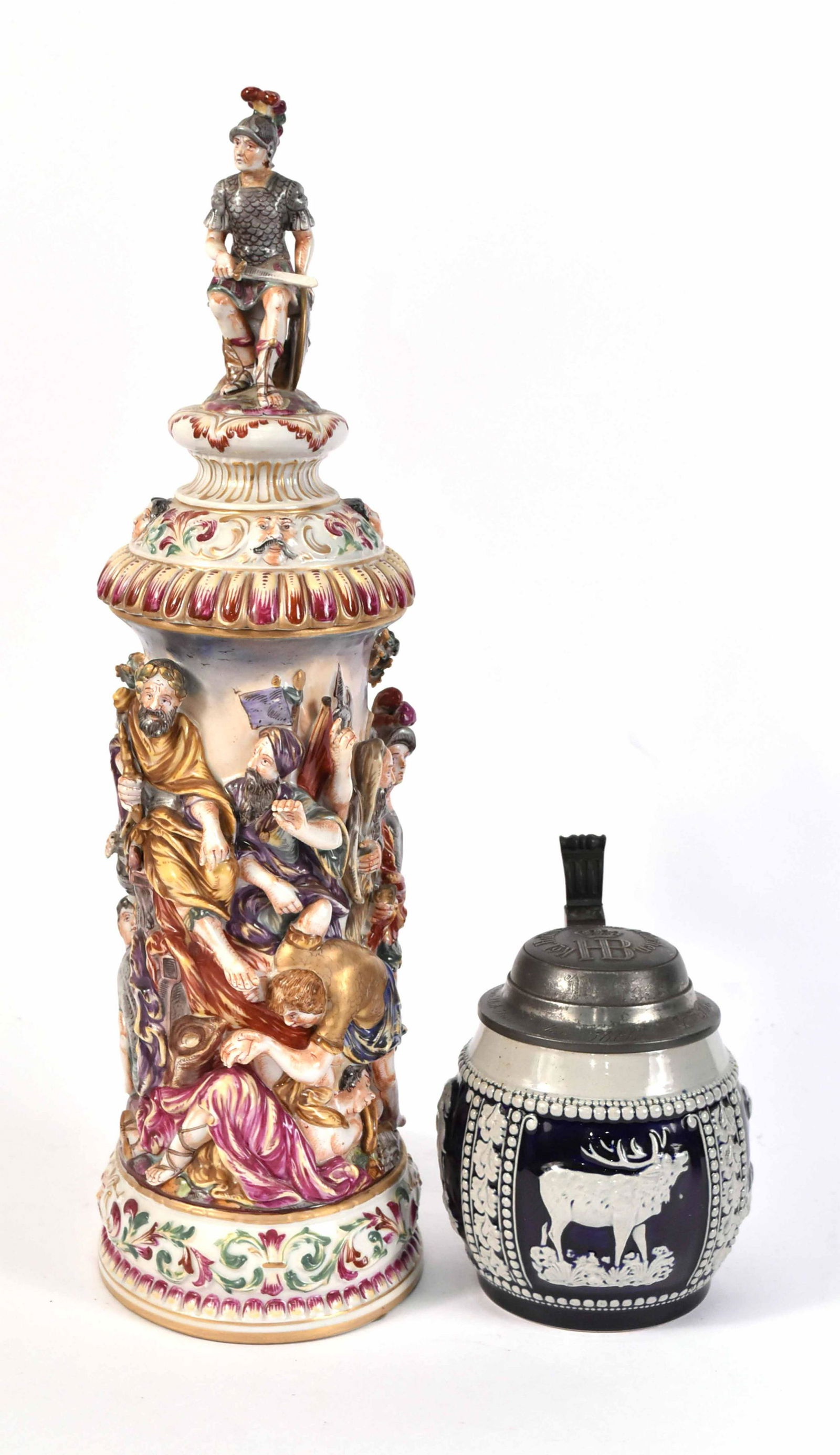 Capodimonte Figural Porcelain Stein: Depicting a classical battle scene, inscribed underside "Al Principe Carlo Albano Francesco." Together with a German stoneware stein. 2 pieces 17"h and 6"h