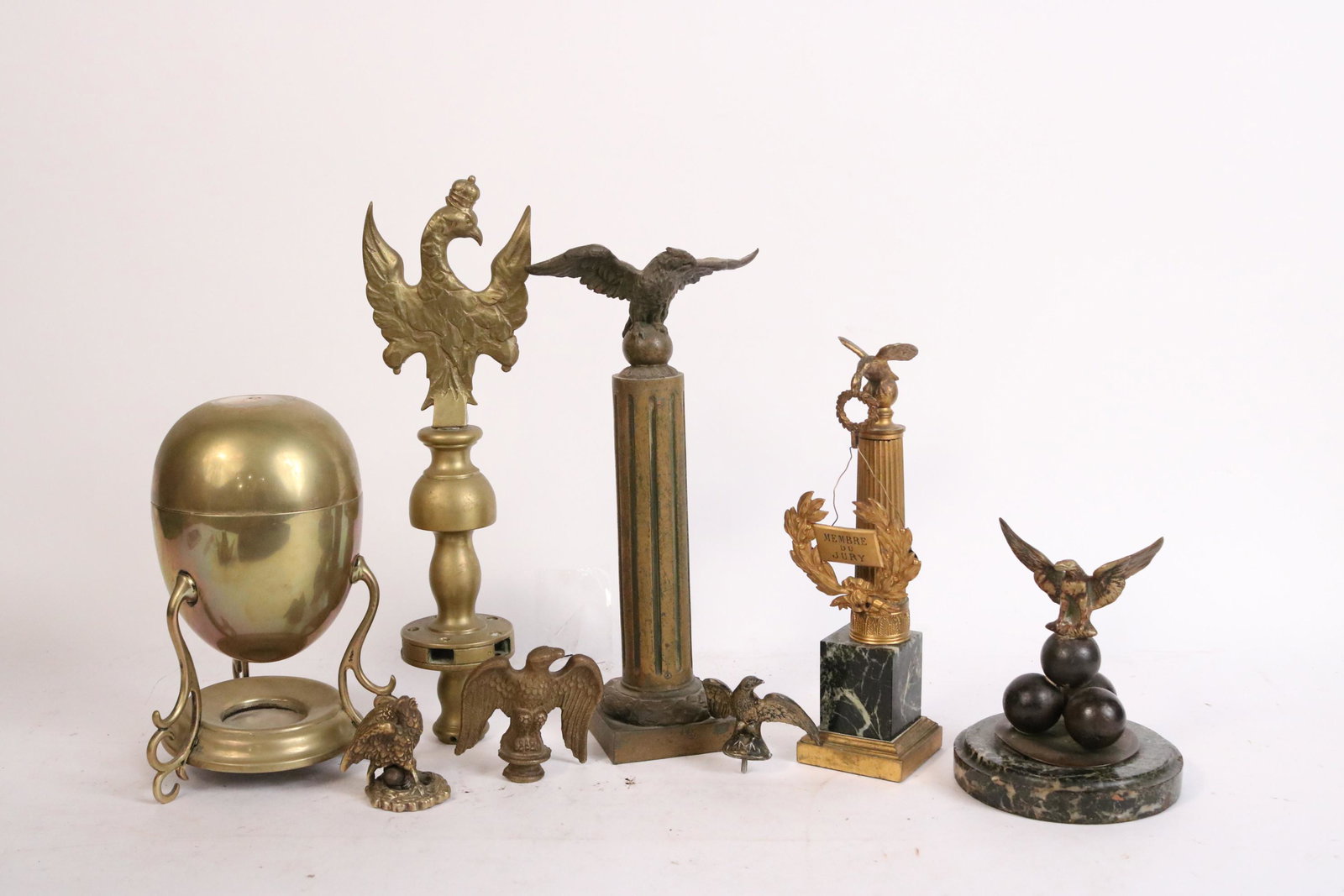 Eight Metal Eagle-Decorated Table Articles: Comprising, four finials, two columns, one eagle balanced on cannonballs, and a brass warmer with eagle finial. Losses to eagle finial on warmer. Tallest: 10-3/4"h