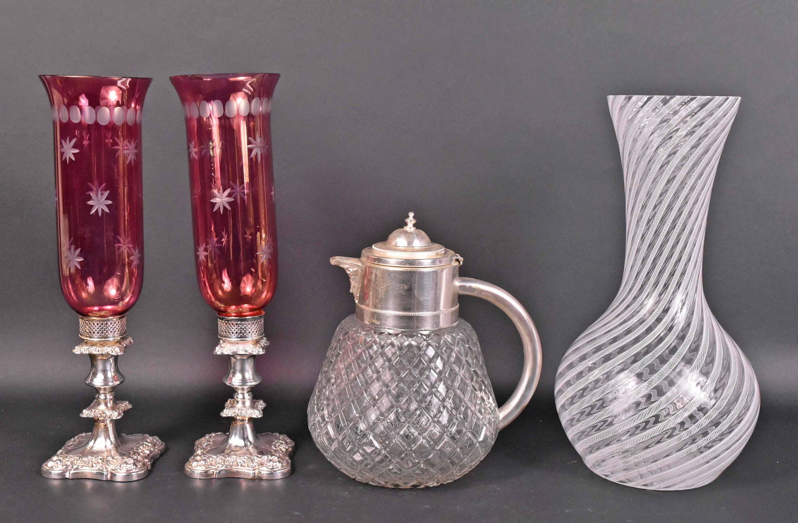 Pair of Silver Plate Candlesticks: With cranberry glass shades. Together with a white metal mounted molded glass pitcher, and a swirl pattern art glass vase. 11"h, 15-1/4"h and 15-3/4"h Provenance: Property from a Private Collection Il