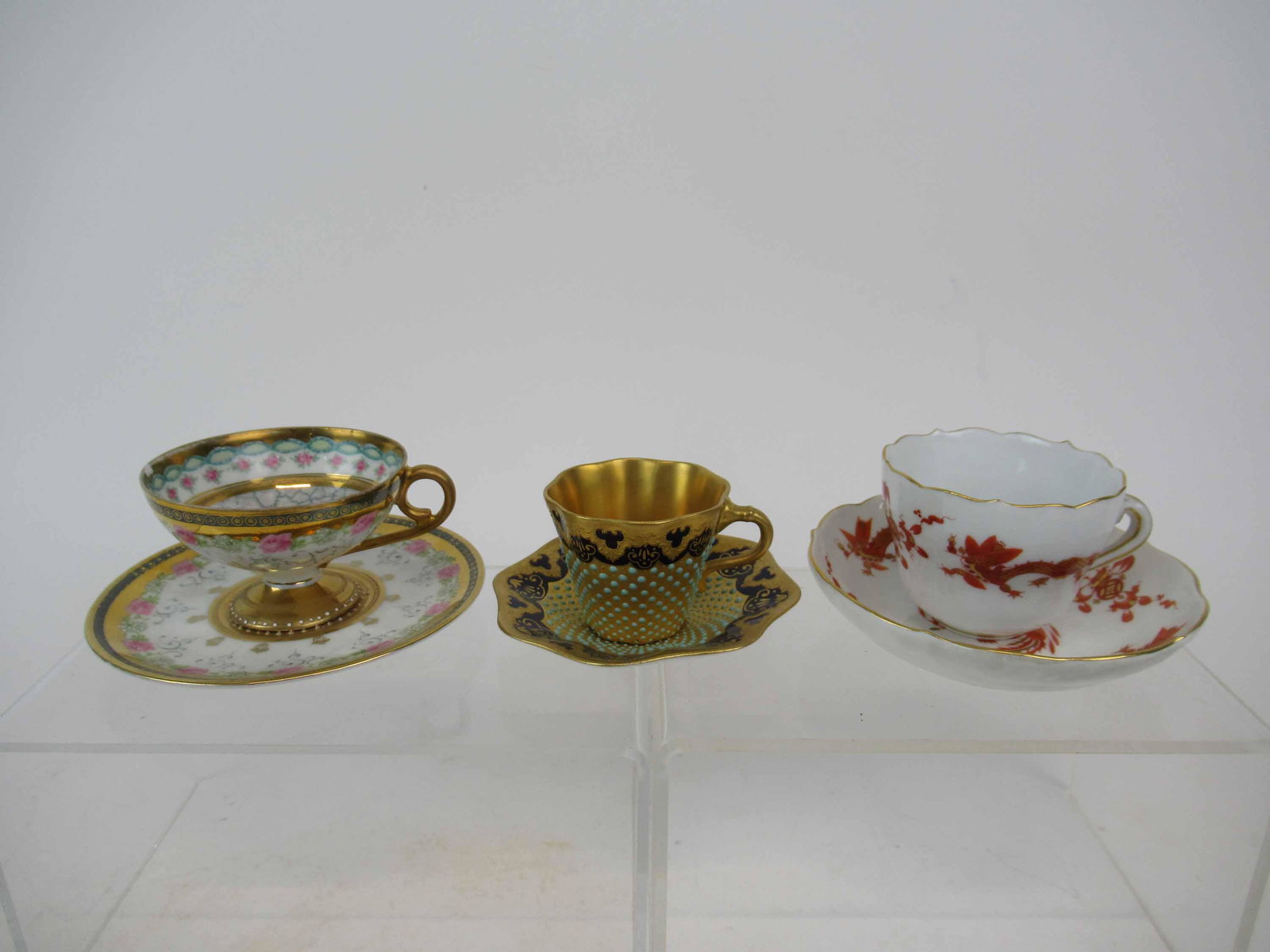 Coalport Jeweled Demi Tasse Cup and Saucer: Coalport Jeweled Demi Tasse Cup and Saucer. Together with Meissen gold gilt red dragon and gilt floral decorated demi tasse cup's and saucers. Used condition, Coalport has hairline to cup and odd cup