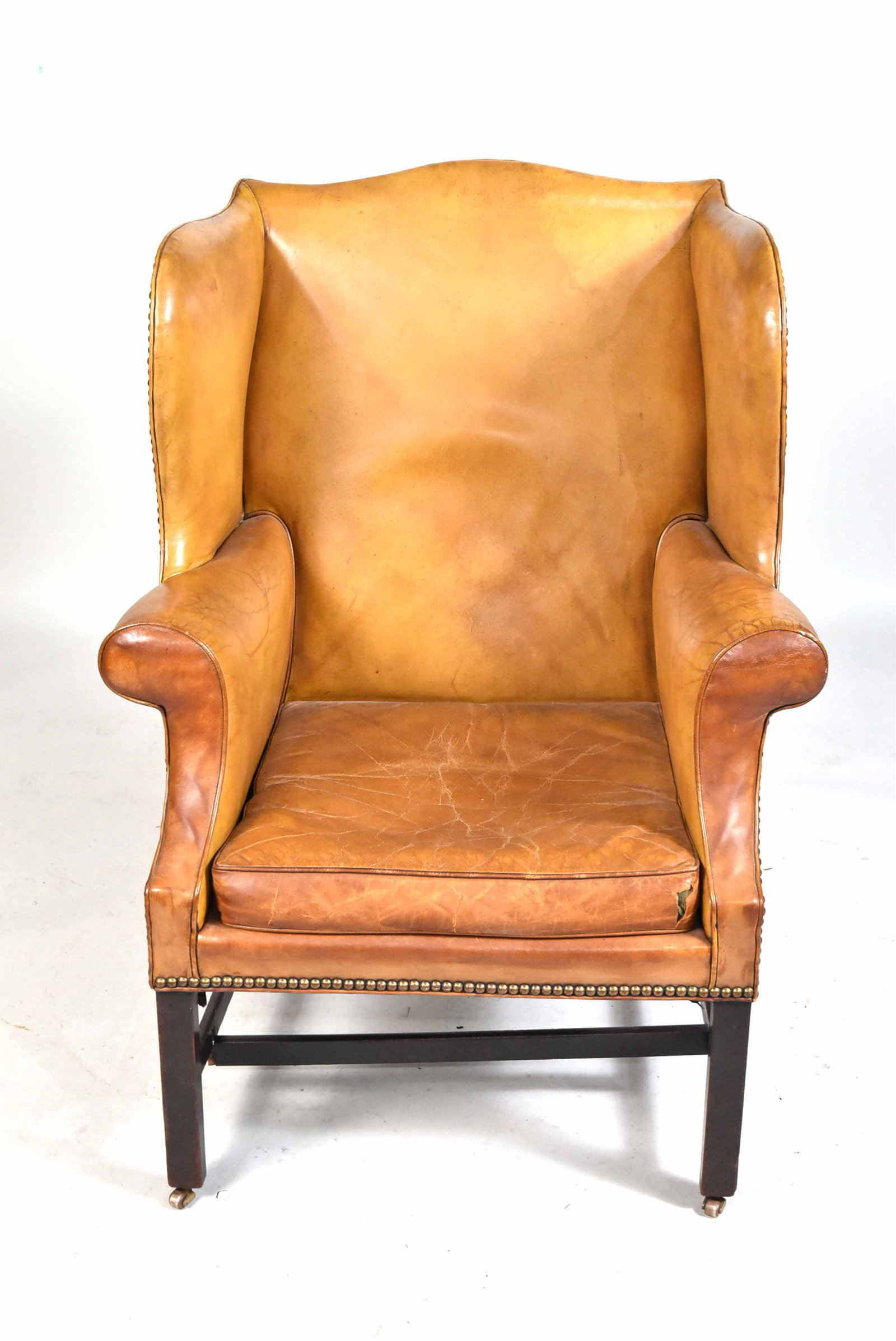 George III Mahogany Wing Armchair: English, third quarter 18th C., with close-nailed pale brown leather upholstery. 44"h Property from the Estate of Ralph & Roberta Carpenter.