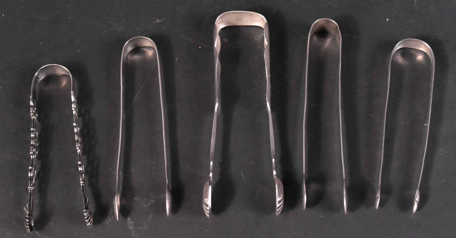 Five Sterling and Coin Silver Sugar Tongs: Of various makers including: James Hyde, Clement Oskamp and Thomas Wallis. Apx. 6 t.o. and 6.5"l Provenance: Property from the Collection of Myrna and Bernard Posner.