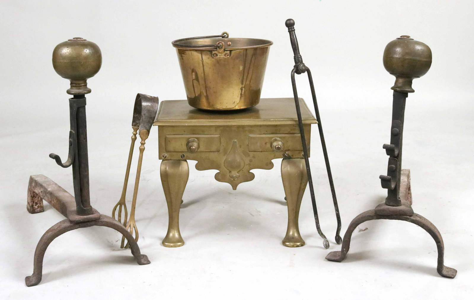 Pair of Brass and Wrought Iron Andirons: Continental, 17th C. Together with a brass footman, English, 19th C., two pairs of tongs, and a brass bucket. 6 pieces Provenance: Property from the Estate of Judith Applegate, Princeton, NJ.