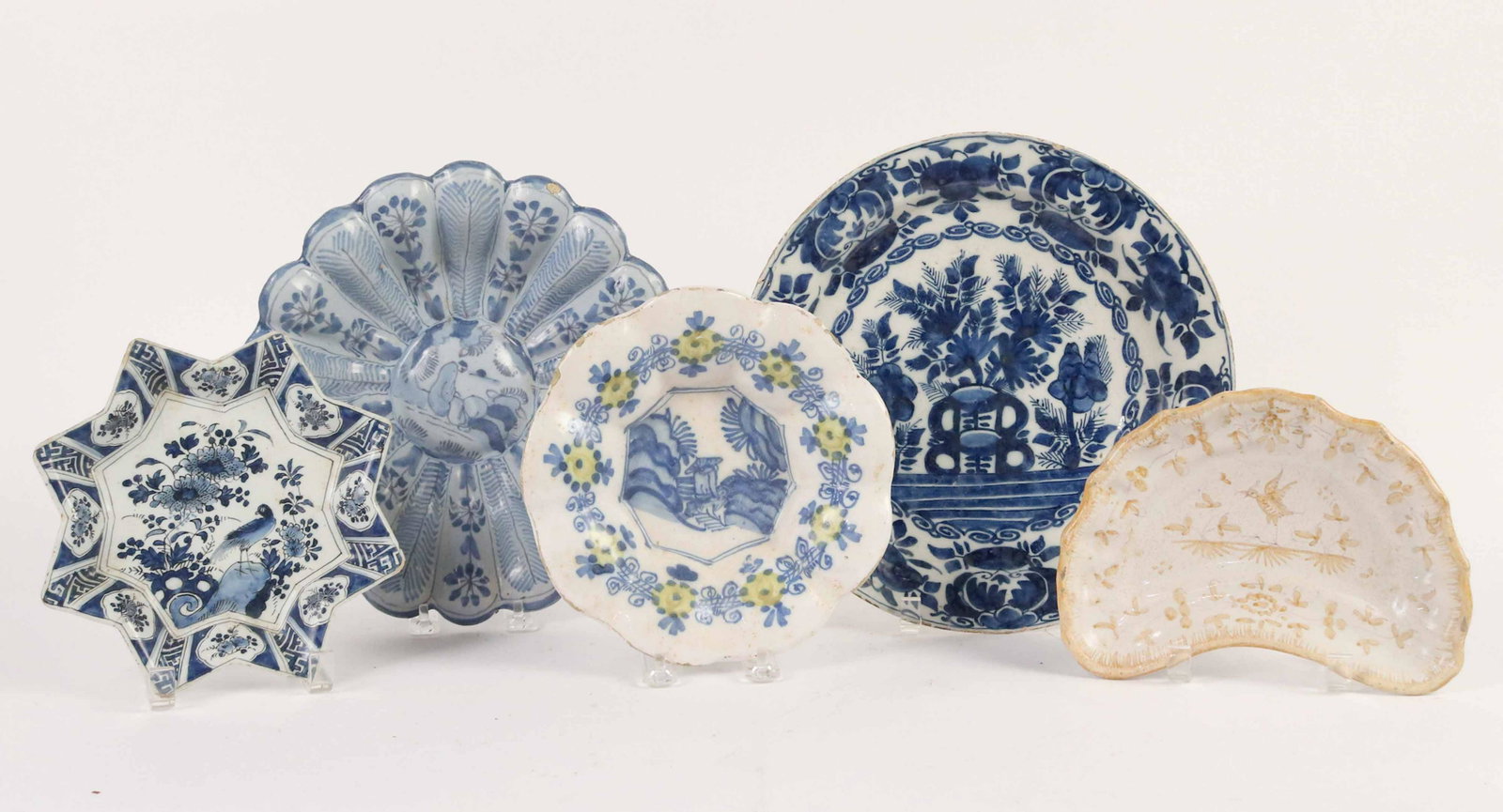 Five Tin Glazed Earthenware Plates: Comprising an early 18th Century German Delft deep lobed plate, an 18th Century French Faience Chinoiserie crescent form plate, an early 18th Century Dutch five pointed star plate, an 18th Century Dut