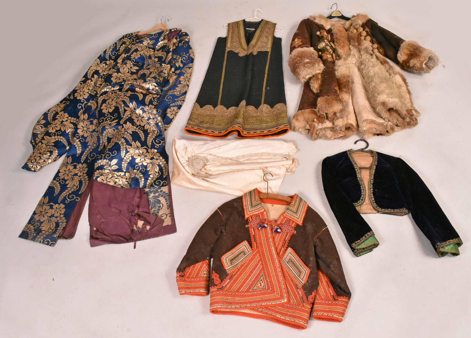 Group of Ottoman Clothing: Including a blue and gold wedding dress, gold embroidered vest, fur trimmed coat, an embroidered wool jacket and a velvet bolero jacket. Together with a silk and faux pearl 1920's flapper dress. Prove