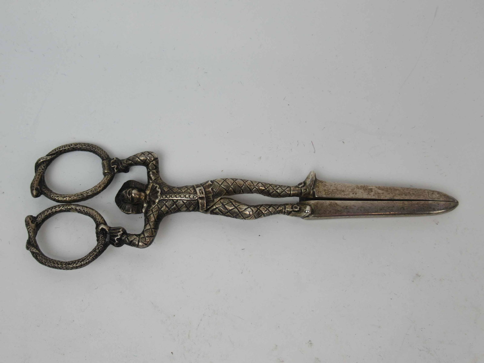 Pair of Victorian Sterling Silver Grape Scissors: Pair of Victorian Sterling Silver Grape Scissors with Harlequin figure holding serpent ring form handles by Henry John Lias. Used condition, 6" long