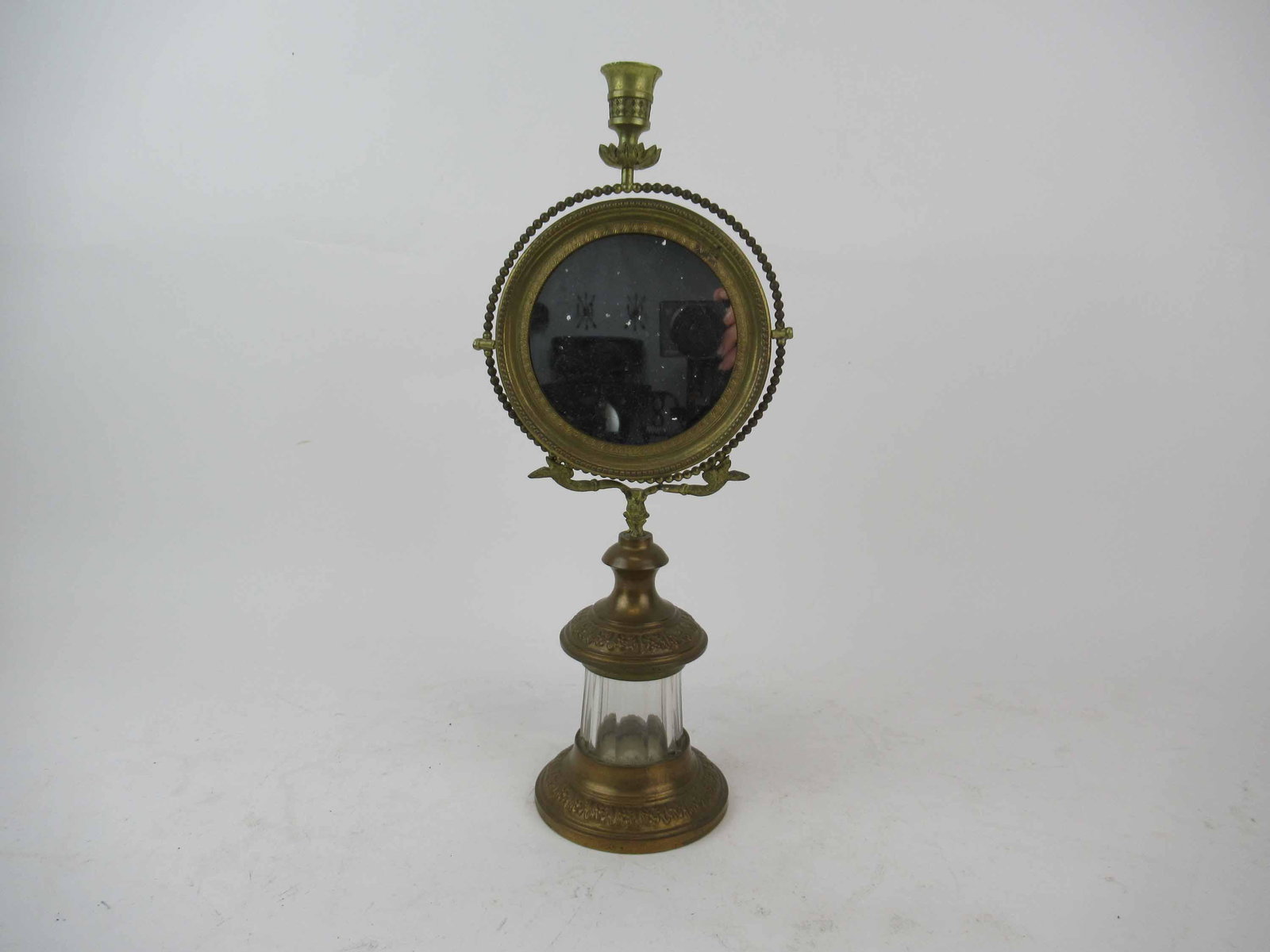 Antique Brass Ladies Vanity Dresser Mirror: Antique Brass Ladies Vanity Dresser Mirror. Having central candle finial above circular mirror. Used condition, wear, worn, break to base arm. 15 1/4" tall x 6 1/2" wide