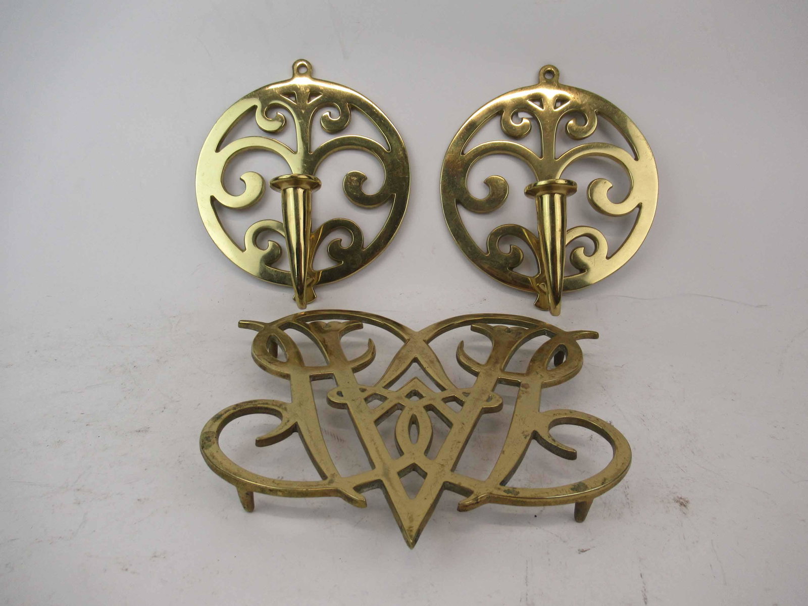 Pair of Virginia Metalcrafters Brass Wall Sconces: Pair of Virginia Metalcrafters Brass Wall Sconces. Together with a Brass Virginia Metalcrafters Queen Ann cypher trivet. Used condition, 8 3/4" tall x 2 3/4" deep