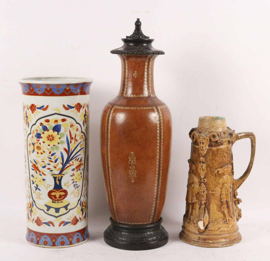 Leather Covered Ceramic Baluster Form Vase: With cast iron lid. Together with a ceramic umbrella stand and a Francis Statuary Co, Cleveland ceramic figural stein of impressive size. Size: Tallest 28 1/2"h