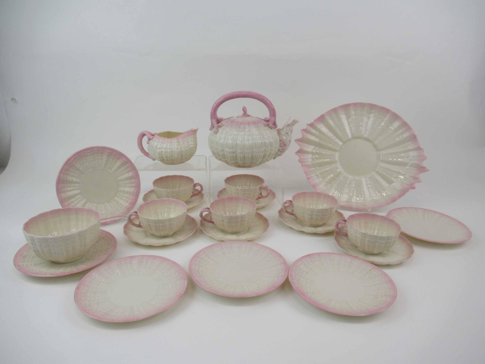 Belleek Black Mark Tridacna Pink Tea Set: Belleek Black Mark Tridacna Pink Tea Set. Comprising, Handled tea pot, cake plate minor chip, creamer and sugar small chip, 6 cups and saucers, Six 6" plates some have glazed pop holes. Used condition