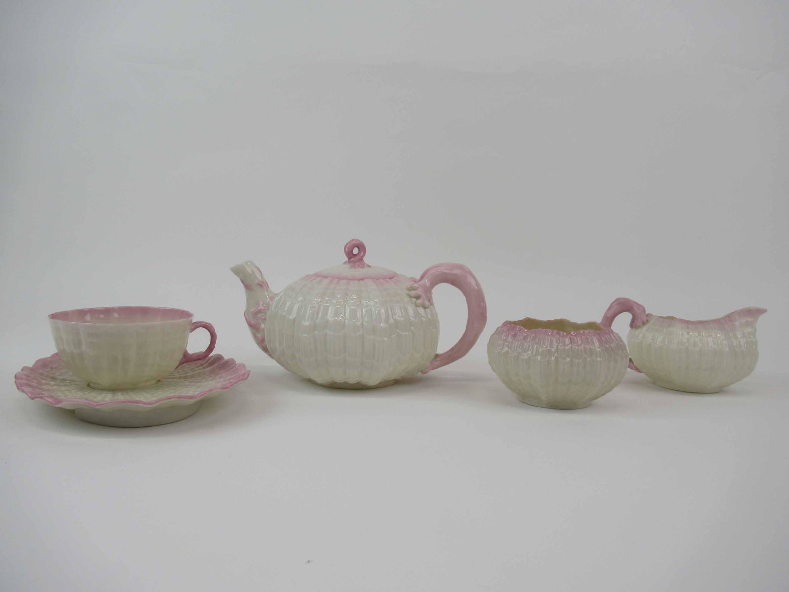 Belleek Black Mark Tridacna Pink Tea Set: Belleek Black Mark Tridacna Pink Tea Set. Comprising, tea pot small chip on spout, creamer and sugar, and a snack plate has glazed pop holes to it. Used condition.