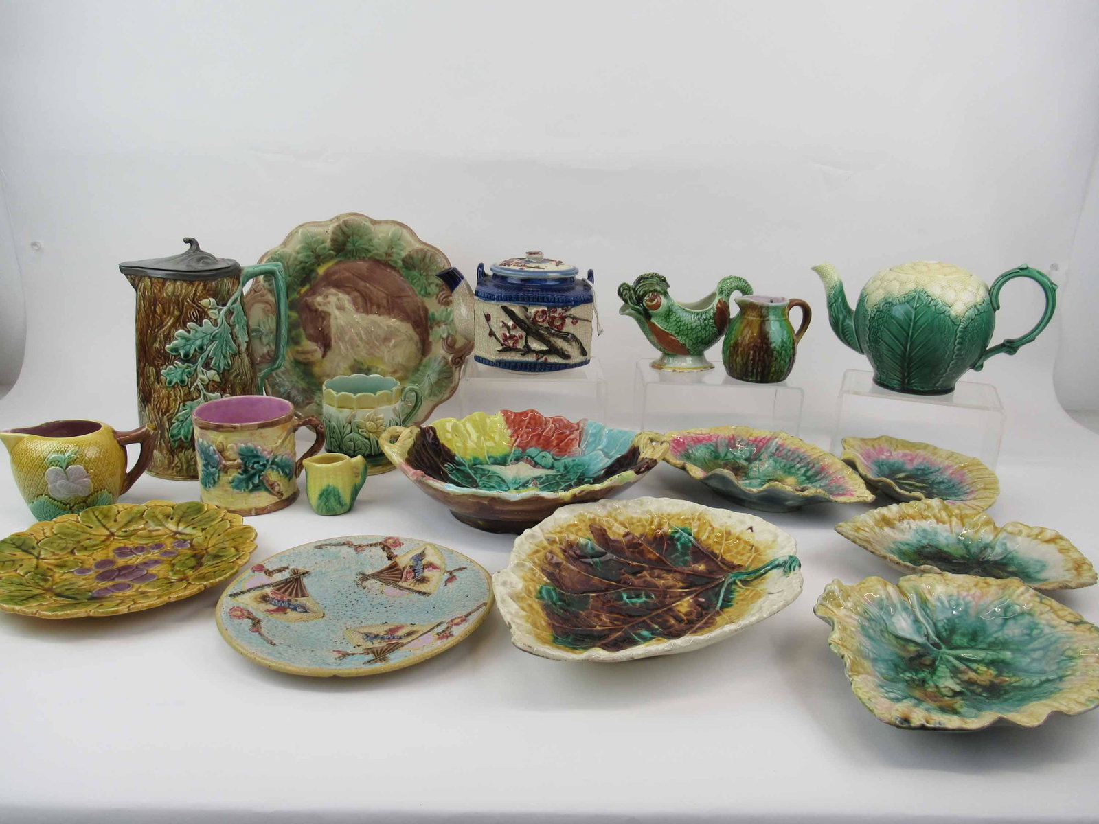 Group of Assorted Majolica Tableware: Group of Assorted Majolica Tableware. Including leaf plates, pitchers, jugs, tea pots, mugs, bowl, dog plate, floral bowl and fruit plate. Some marked Griffen Smith and Hill. Used condition, some chip
