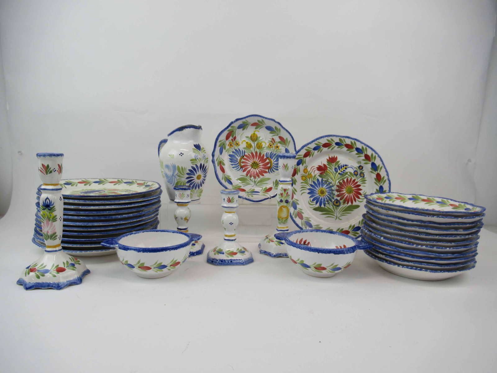 Quimper Fleuri Royal Partial Dinnerware Service: Quimper Fleuri Royal Partial Dinnerware Service. Comprising 12 dinner 12" diam., 12 bowls 8 3/8" diam., 2 lugged bowls, 2 pairs of candlesticks and pitcher. Used condition,chips, wear, worn, knife mar