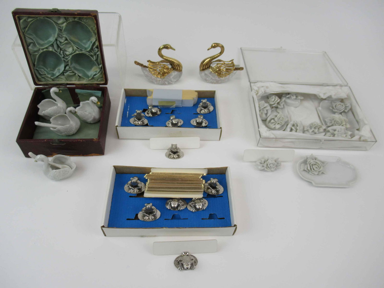 Set of 4 Porcelain Swan Salt Cellars: Set of 4 Porcelain Swan Salt Cellars. Together with a Pair of Crystal Swan salt cellars, 2 boxes of six frog place card holders and a group of 8 porcelain place card holders having some chips.