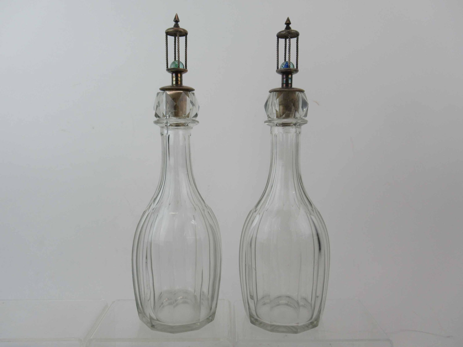 Pair of Antique Glass Silver Stoppered Decanters: Pair of Antique Glass Silver Stoppered Decanters. Each having silver plated stoppers with inset marbles. Used condition, chips, 14 1/4" tall x 3 1/2".